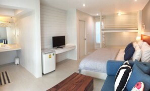 A compact hotel room with a bunk bed, a small desk with a TV, a refrigerator, and a sofa with pillows. - Zea Za Bungalow (Hua Hin)