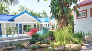 Un jardín con piscina, mobiliario exterior y un edificio de techo azul.