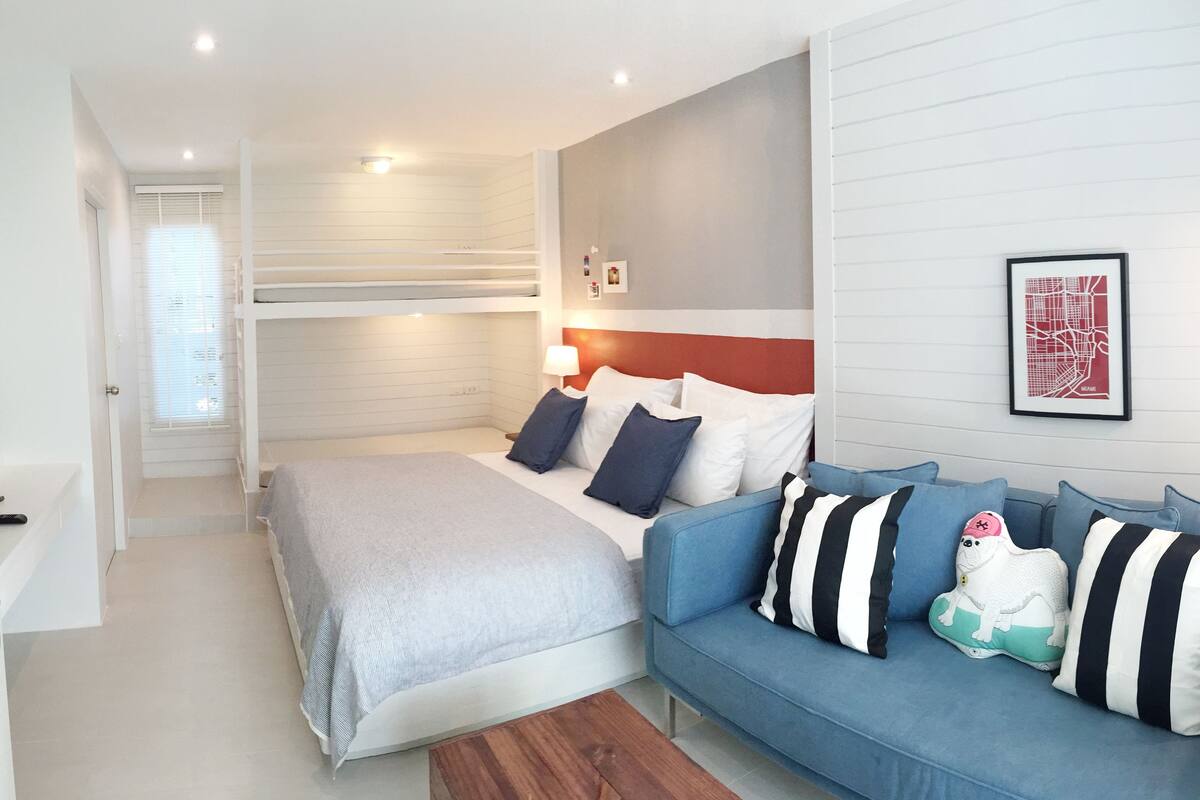 A bedroom with a bunk bed, a sofa, and a TV.