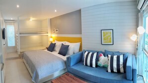 Un dormitorio con cama, sofá, mesita de noche, lámpara y ventana.