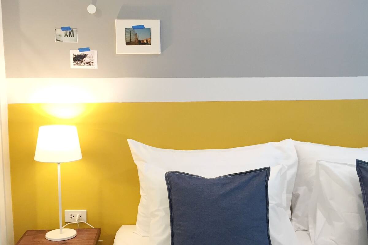 A hotel room with a bed, a nightstand, a lamp, and wall decorations.