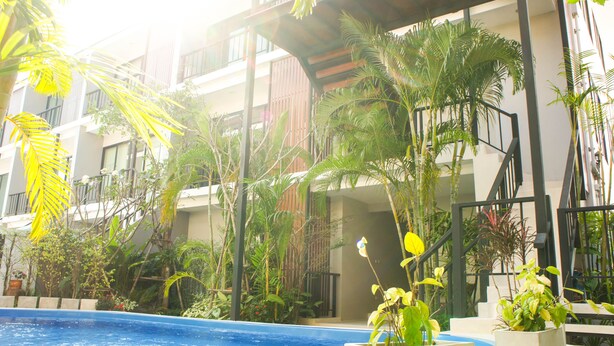 A swimming pool surrounded by lush greenery and modern buildings. - Chaba Place (Hua Hin)