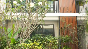 A multi-story building with balconies, a garden area with various plants, and a modern architectural design. - Chaba Place (Hua Hin)