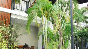 A multi-level outdoor area with a pool, wooden furniture, and various plants. - Chaba Place (Hua Hin)