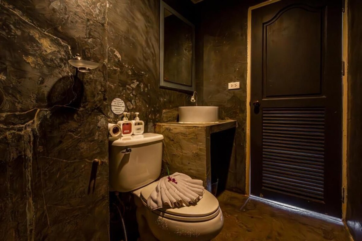 Un baño con un lavabo de mármol, un inodoro con una toalla y una puerta oscura.