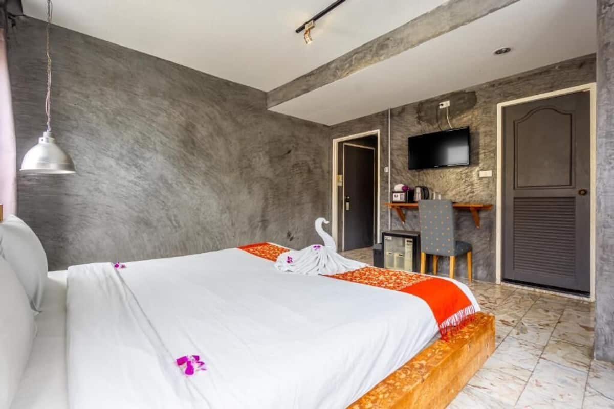 A hotel room with a bed, a desk, a TV, and a door.