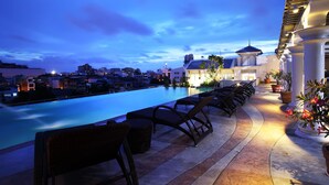 A rooftop pool area with lounge chairs and a view of the city skyline at dusk. - Chillax Resort (Bangkok)
