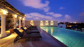 Relax by the serene pool, surrounded by shaded walkways and a city view.