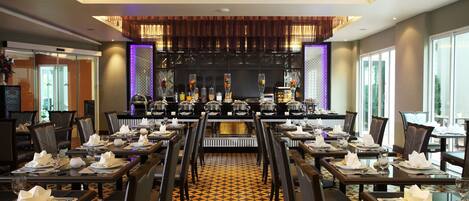 Een restaurant met een lange toonbank, meerdere tafels en een vloer met een patroon.