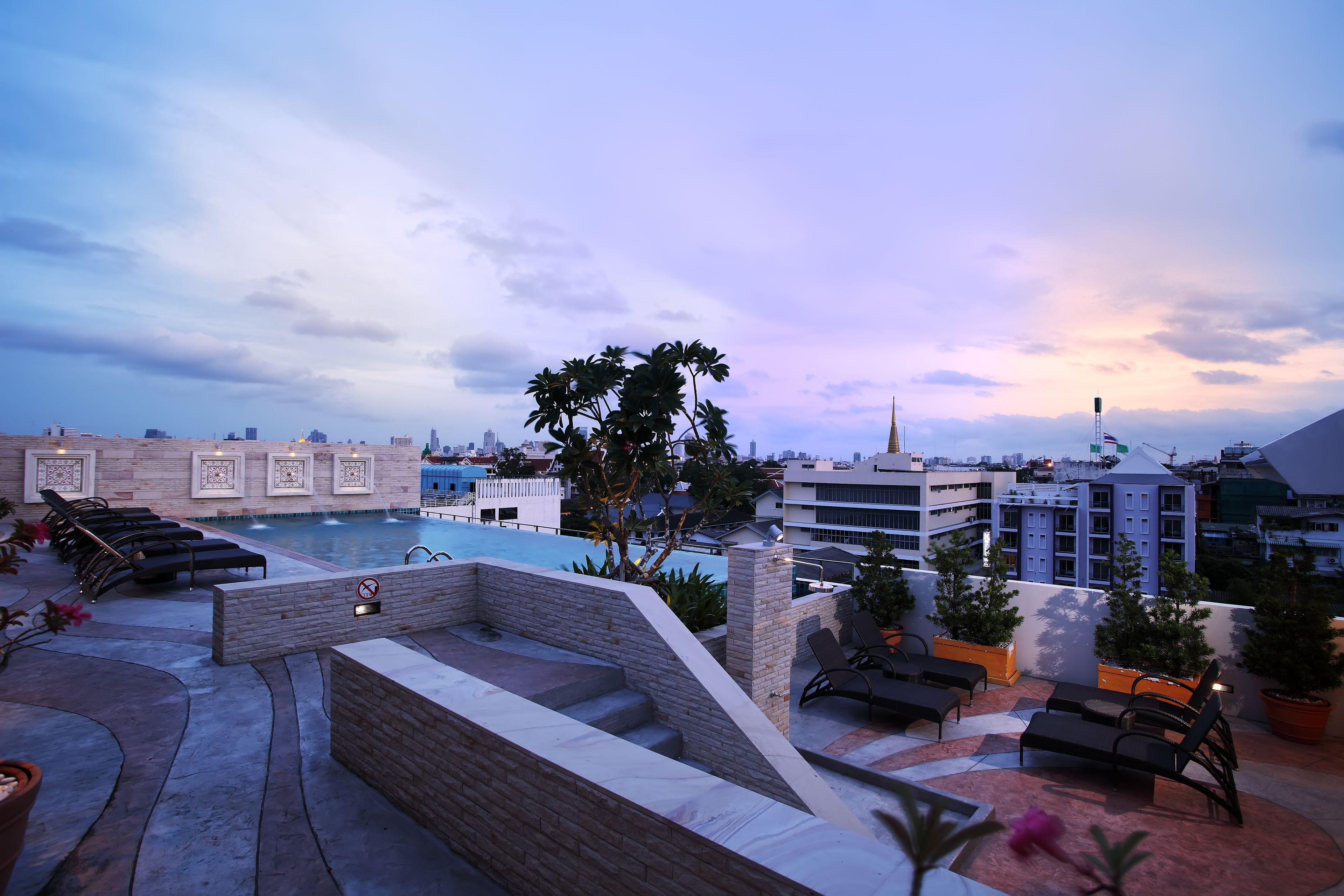 A rooftop pool area with lounge chairs, a small pool, and potted plants.