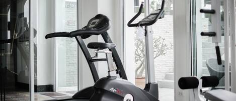 A home gym with two stationary bikes and a treadmill.