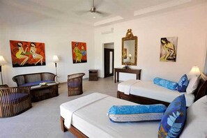 Habitación de hotel con una cama, dos sofás, una mesita y obras de arte en las paredes.