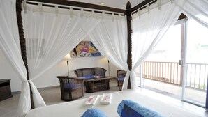 A bedroom with a large bed, a small table with chairs, and a balcony with a railing. - Aquarius Beach Hotel (Denpasar)