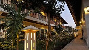 A hotel with a well-lit exterior walkway, a balcony with a railing, and a variety of plants. - Aquarius Beach Hotel (Denpasar)