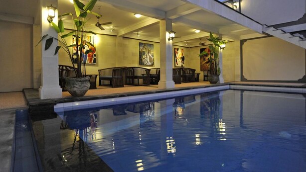 An indoor swimming pool area with a seating area, potted plants, and artwork on the walls. - Aquarius Beach Hotel (Denpasar)