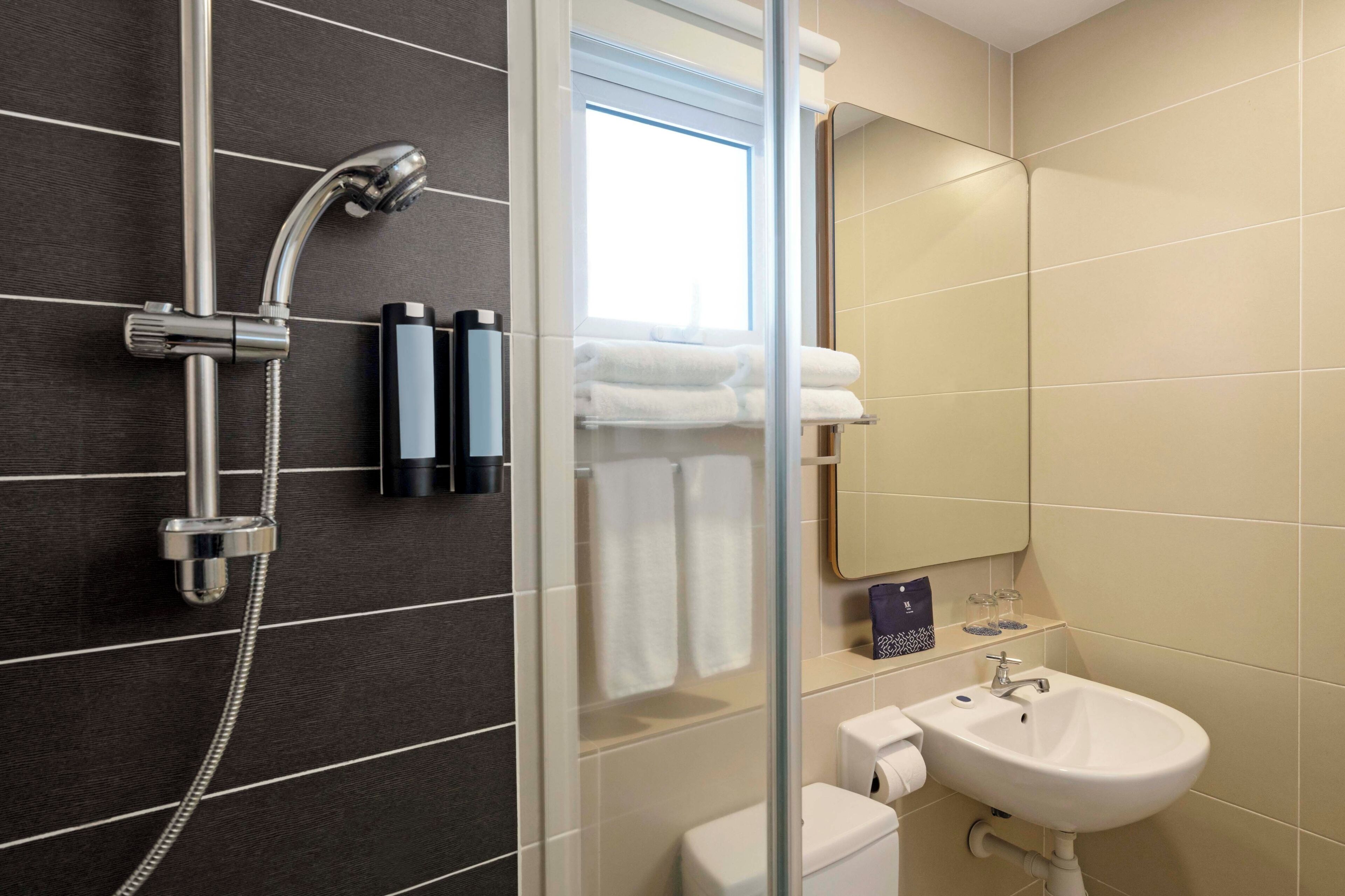 A modern bathroom with a shower, toilet, sink, and a mirror.