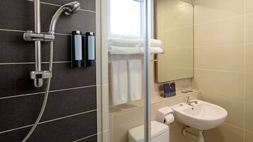 A modern bathroom with a shower, toilet, sink, and a mirror.