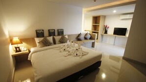 A modern hotel room with a large bed, a bedside table with a lamp, a flat-screen TV, and artwork on the walls. - Memo Suite Pattaya (Pattaya)