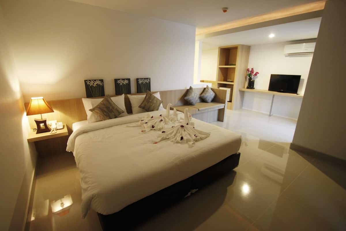 Ein modernes Hotelzimmer mit einem großen Bett, einem Nachttisch mit Lampe, einem Flachbildfernseher und Kunstwerken an den Wänden.