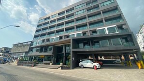 A multi-story building with a modern design, featuring a large entrance and a parking area with several cars. - Memo Suite Pattaya (Pattaya)