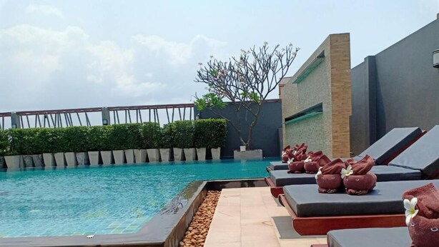 A poolside area with lounge chairs and a view of a bridge. - Memo Suite Pattaya (Pattaya)