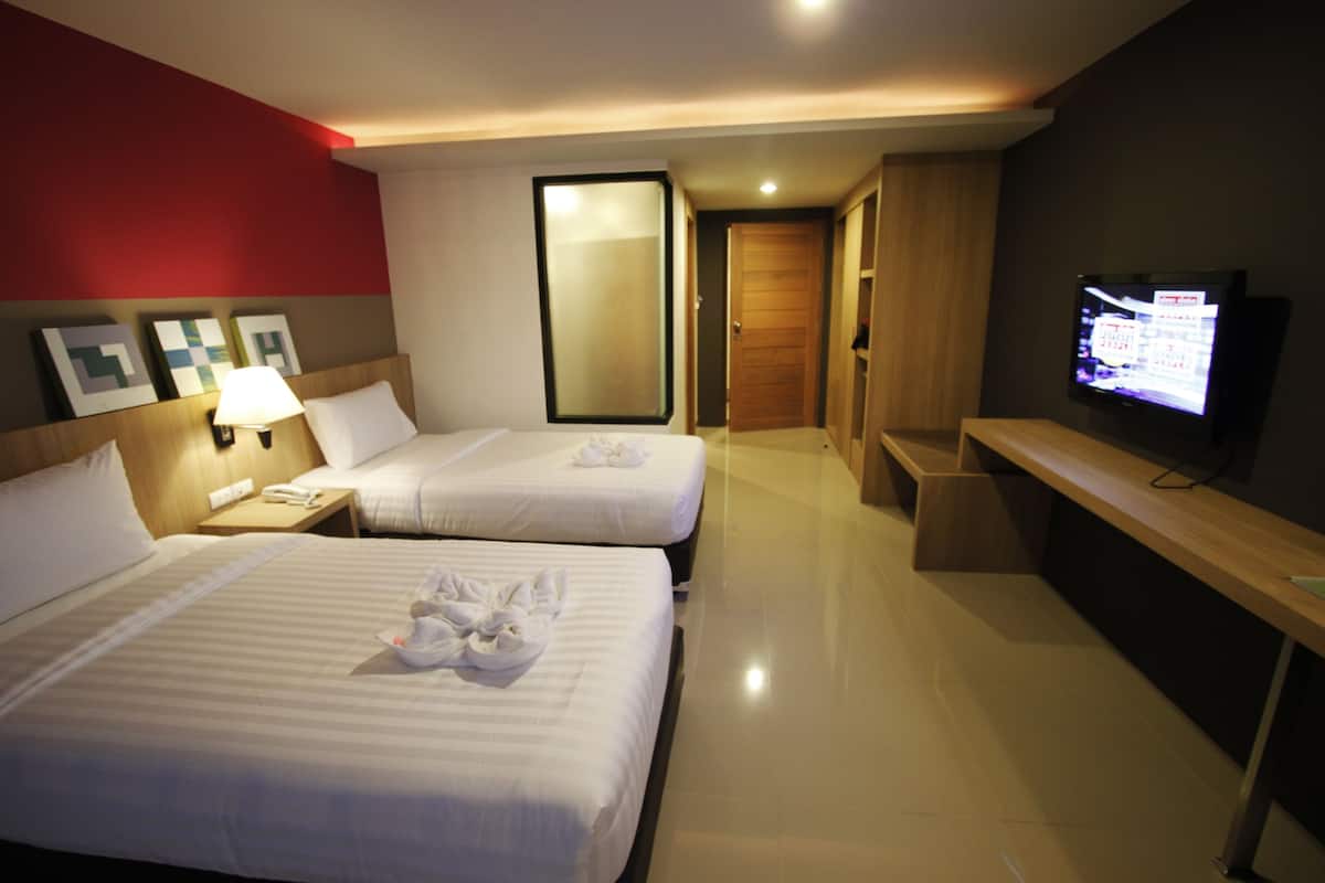 Ein Hotelzimmer mit zwei Betten, einem Fernseher, einem Schreibtisch und einem Spiegel.