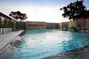 A swimming pool with lounge chairs and a brick wall. - Memo Suite Pattaya (Pattaya)