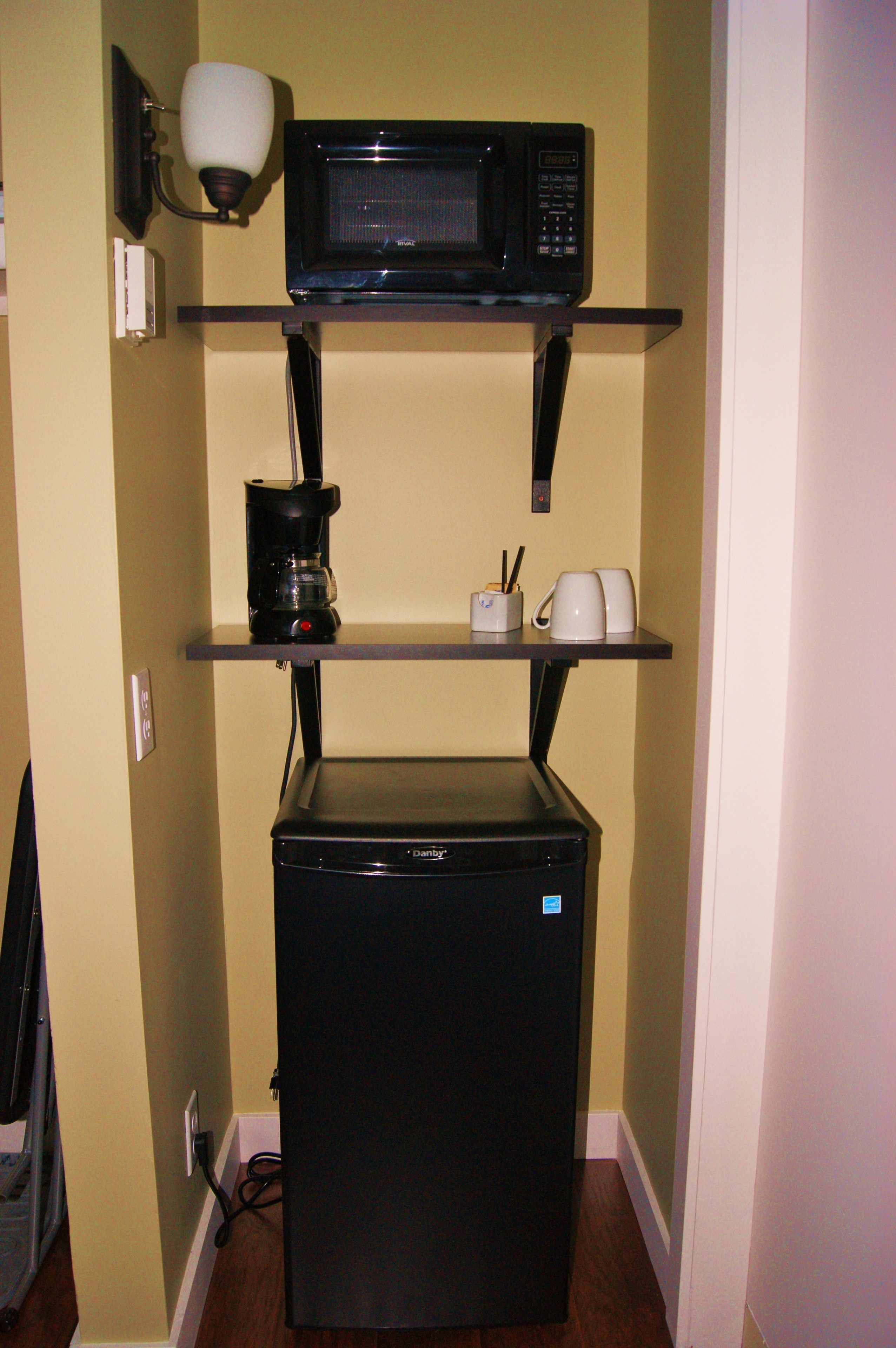 A compact kitchenette with a microwave, coffee maker, and a small refrigerator.