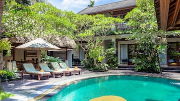 Una piscina al aire libre, sillones reclinables de piscina