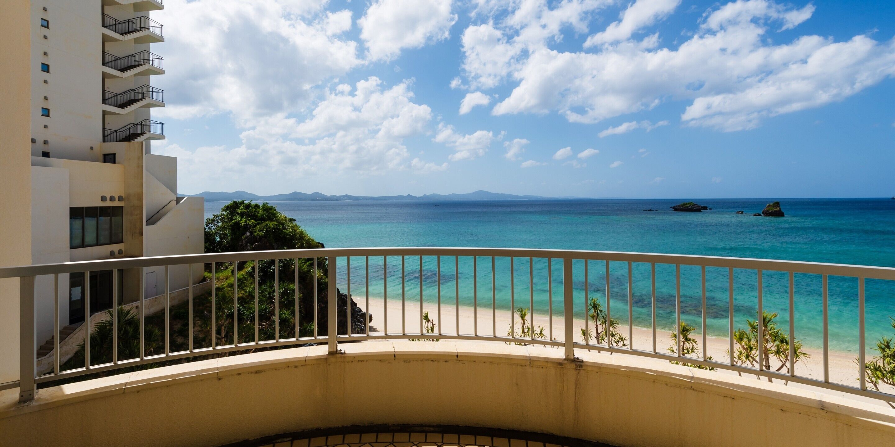 A balcony with a view of a beach and ocean.