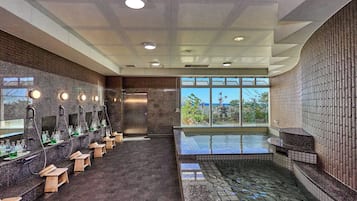 Ein modernes Badezimmer mit mehreren Waschbecken, einem großen Fenster und einem Whirlpoolbereich.