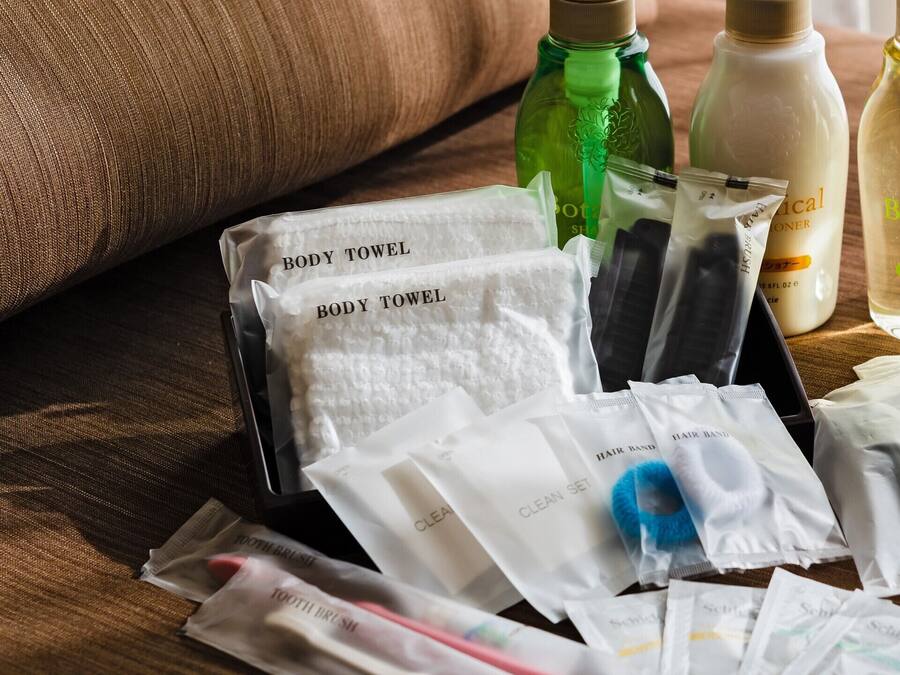 A variety of toiletries and personal care items, including body towels, hair brushes, and bottles of shampoo and body wash, arranged on a wooden surface.