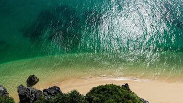 Ein Strand mit klarem türkisblauem Wasser, Sandstrand und Felsformationen.