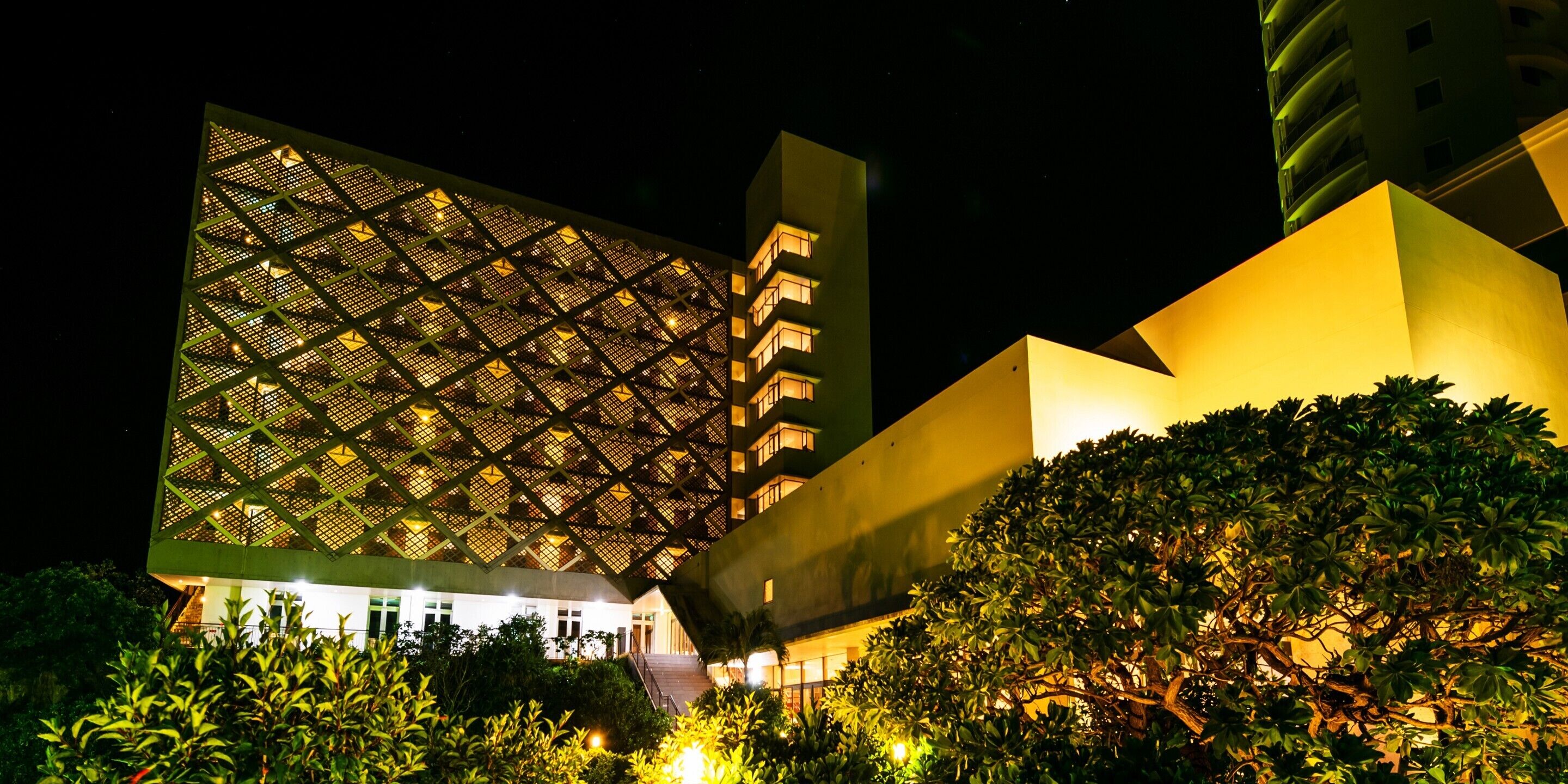 A modern building with a geometric facade and a well-lit entrance.