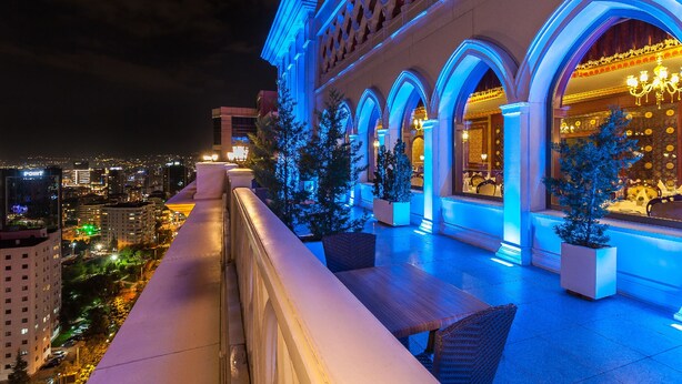 A hotel with a balcony overlooking a cityscape at night. - Meyra Palace (Ankara)