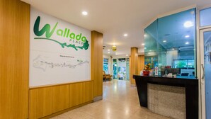 Una zona de recepción con un gran cartel que dice 'Wallada Place', un mostrador de recepción y un mapa en la pared.