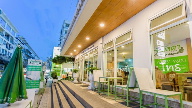 Fachada de hotel con mesas al aire libre, plantas en macetas y señalización clara.