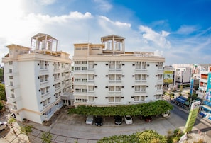 A multi-story residential building with balconies, a rooftop structure, and a parking area with several cars. - Wallada Place (Bangkok)