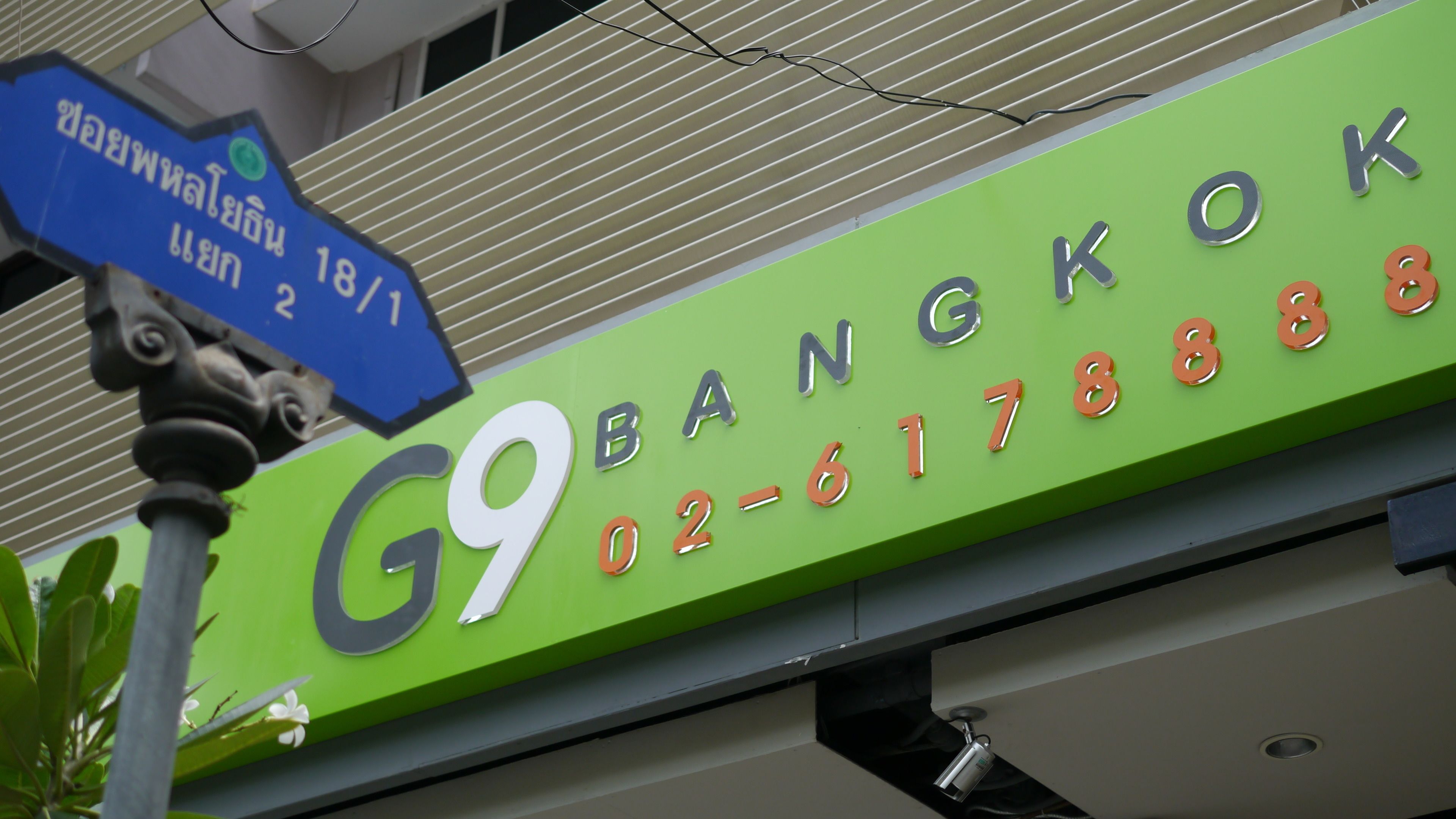 Un letrero verde con el nombre 'Bangkok' y un número de teléfono.
