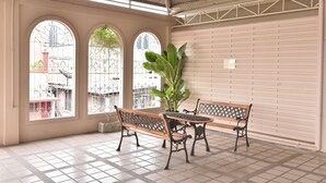 A covered patio with a tiled floor, two wooden benches, a table, and a large potted plant. - G9 Bangkok (Bangkok)