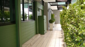 A corridor with green walls, tiled flooring, and potted plants. - G9 Bangkok (Bangkok)
