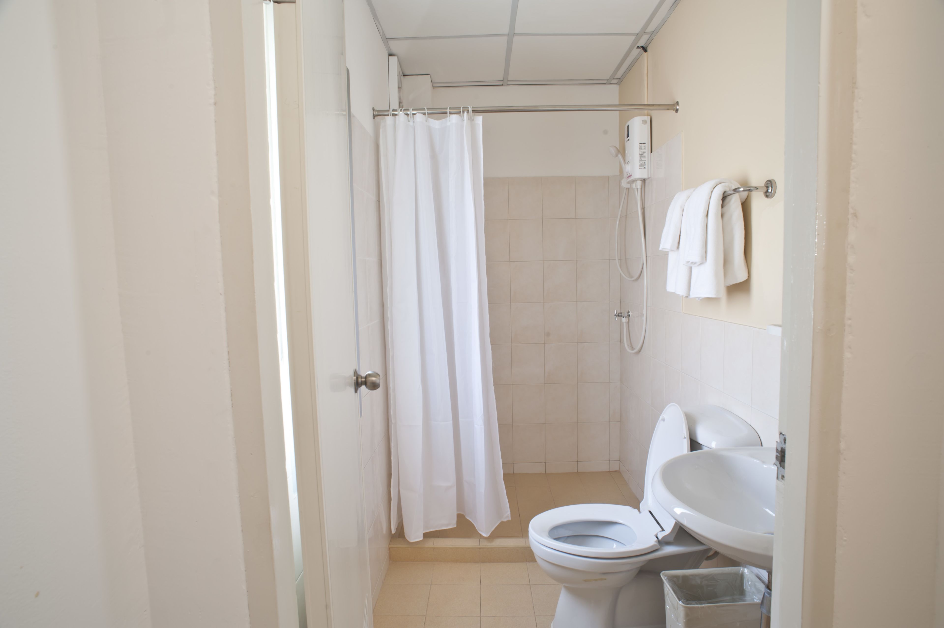 Une petite salle de bain propre, équipée d’une douche, de toilettes et d’un lavabo.