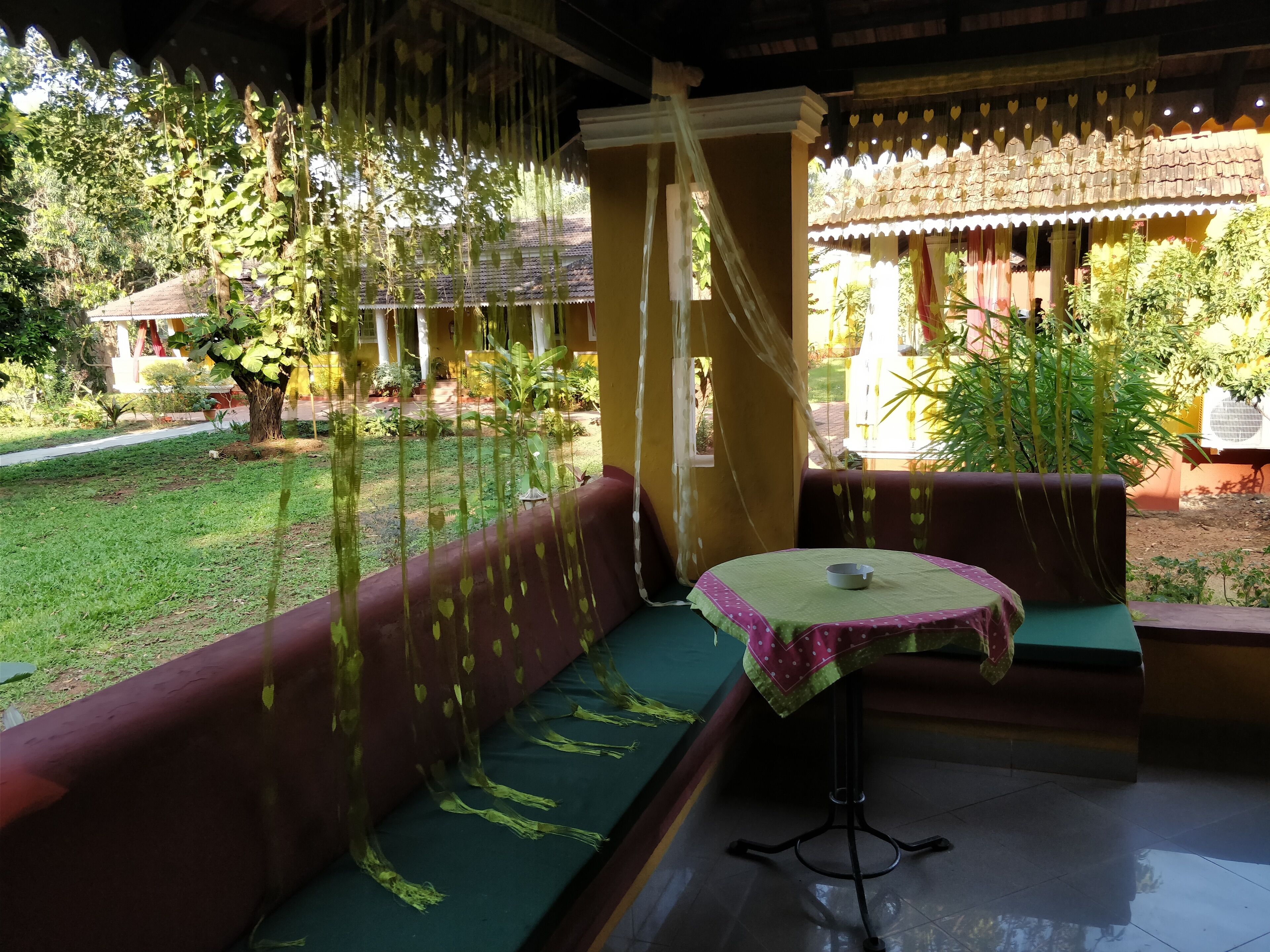 Una habitación con un sofá verde, una mesita con un cuenco y vistas a un jardín y un edificio.