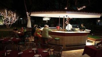 An outdoor dining area with tables and chairs, a bar counter, and a covered seating area.