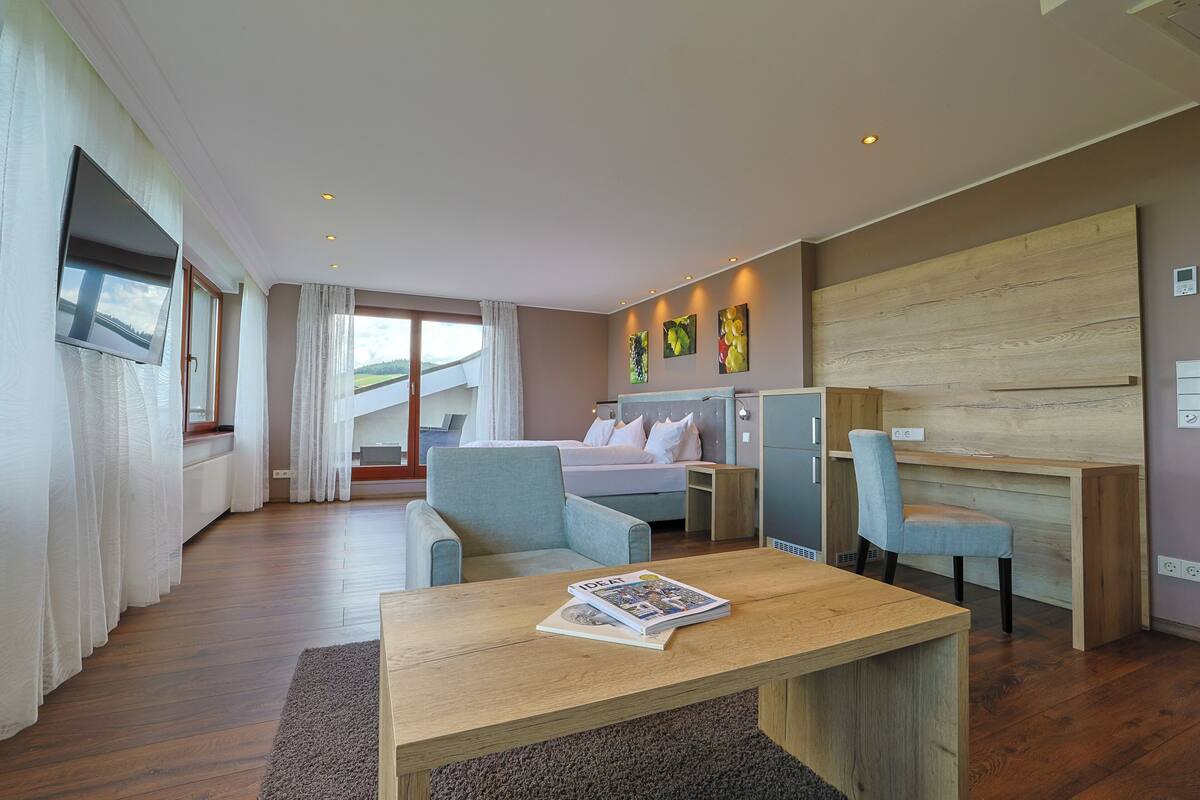 A modern hotel room with a bed, a desk, a chair, and a TV mounted on the wall.