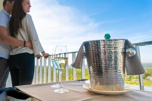 A table with a metallic container and two glasses of white wine, set against a scenic outdoor backdrop. - Hotel Rebenhof (Baden-Baden)