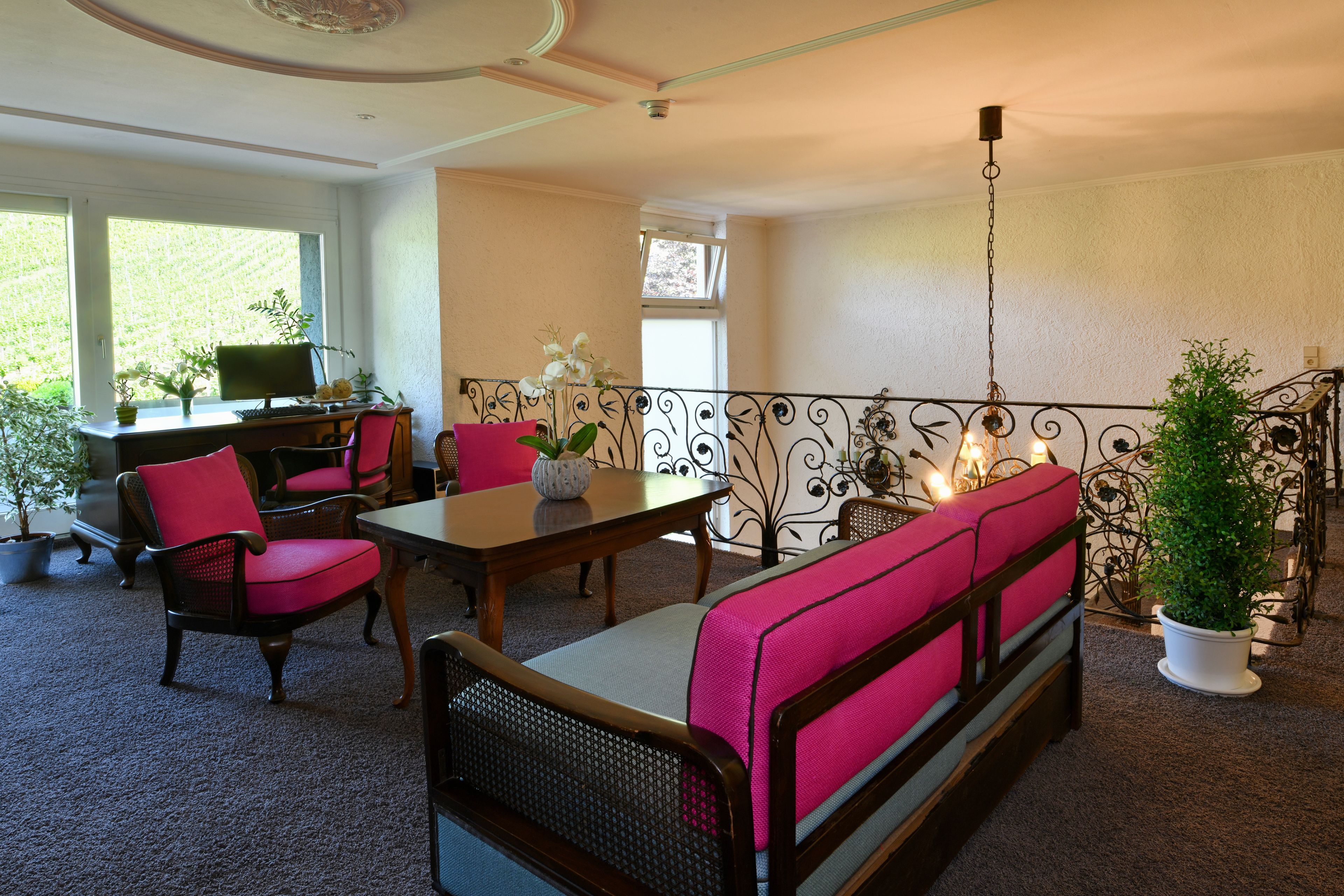 A room with a dining table, chairs, a sofa, and a balcony with a railing.
