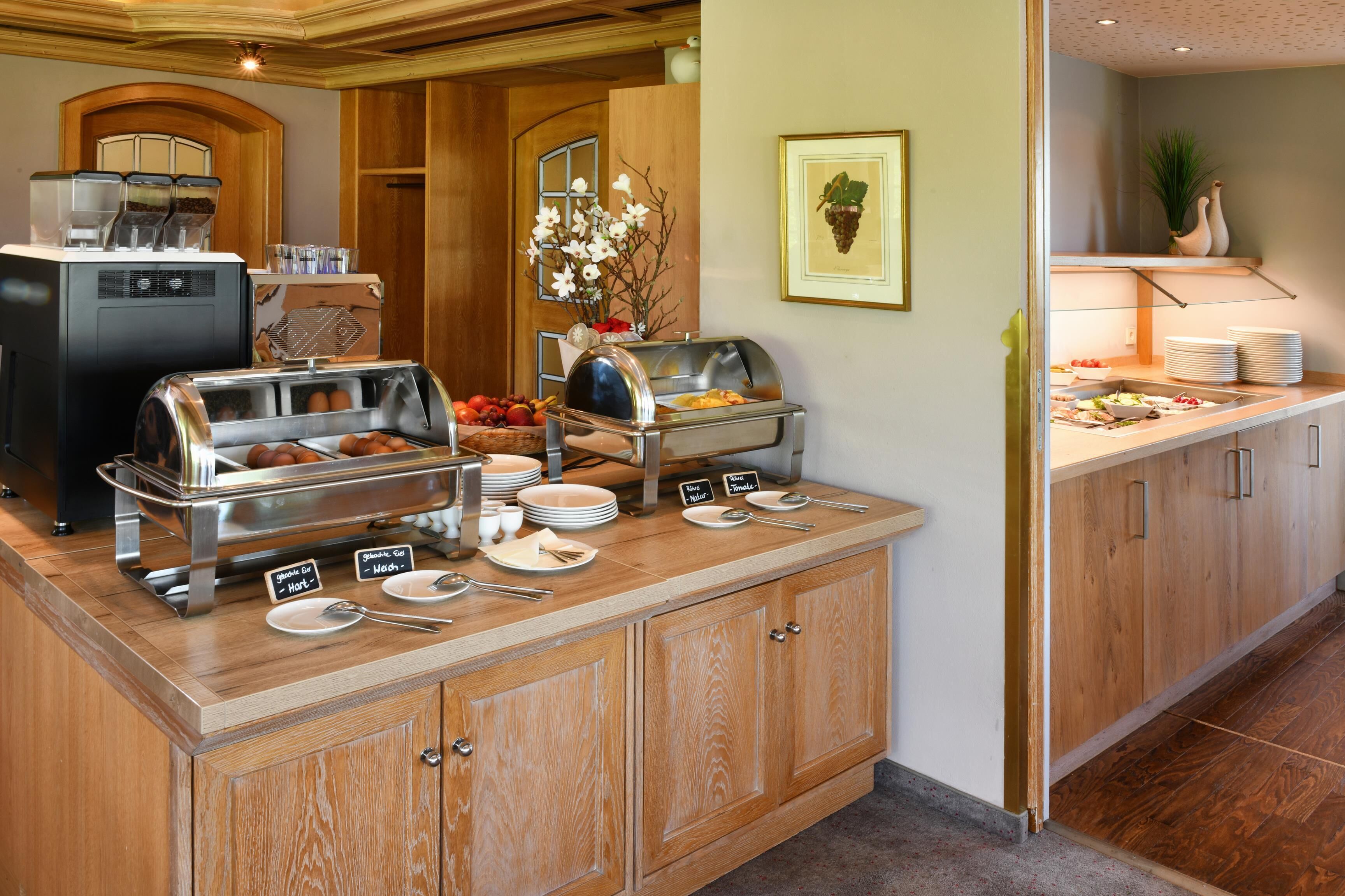 A buffet setup with various food stations, including a coffee machine and a fruit display.