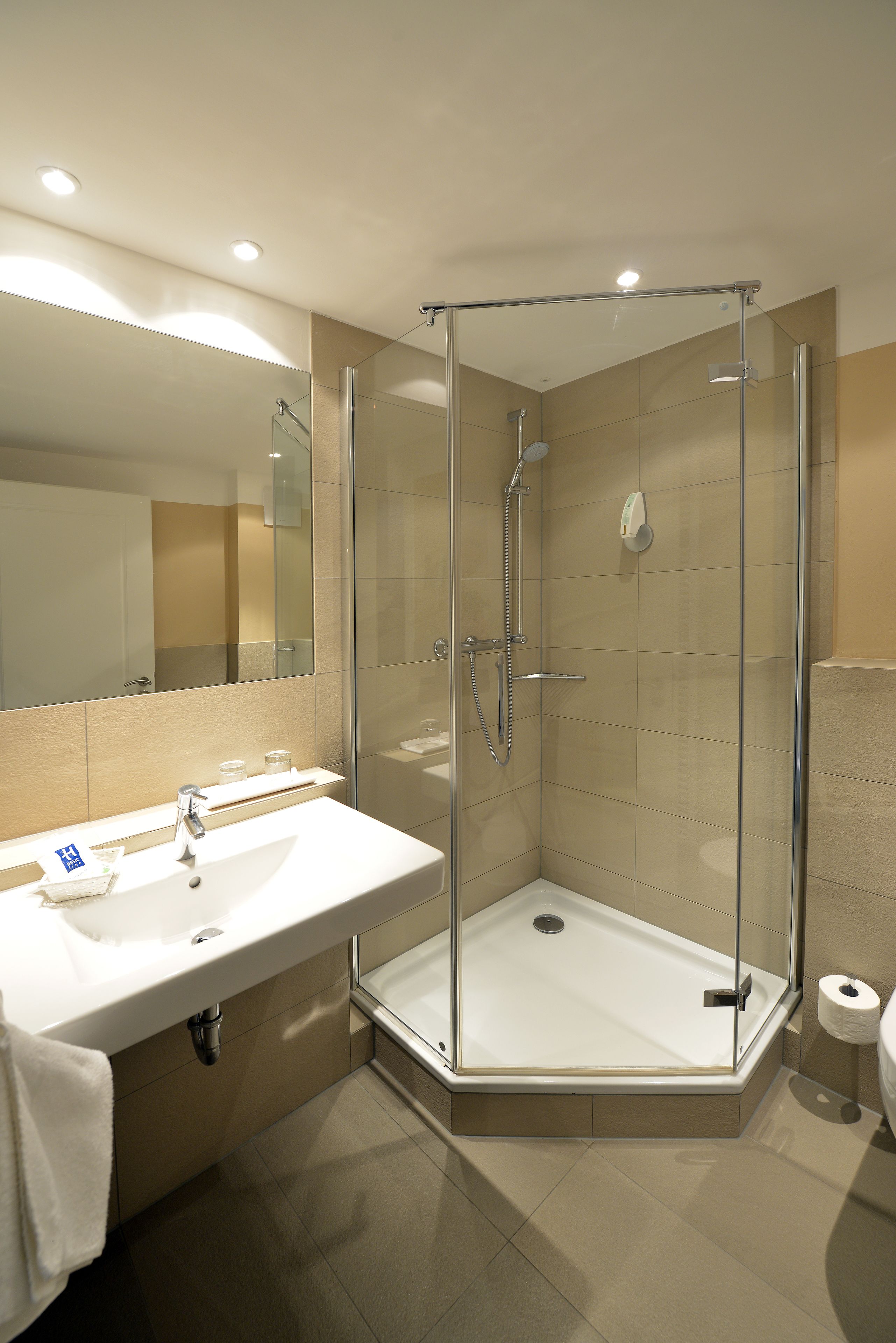 Une salle de bain moderne avec une douche à parois de verre, un lavabo blanc et un grand miroir.