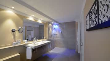 A modern bathroom with two sinks, a large mirror, and a shower area.